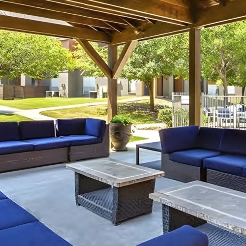 a patio with blue couches and a table and chairs
